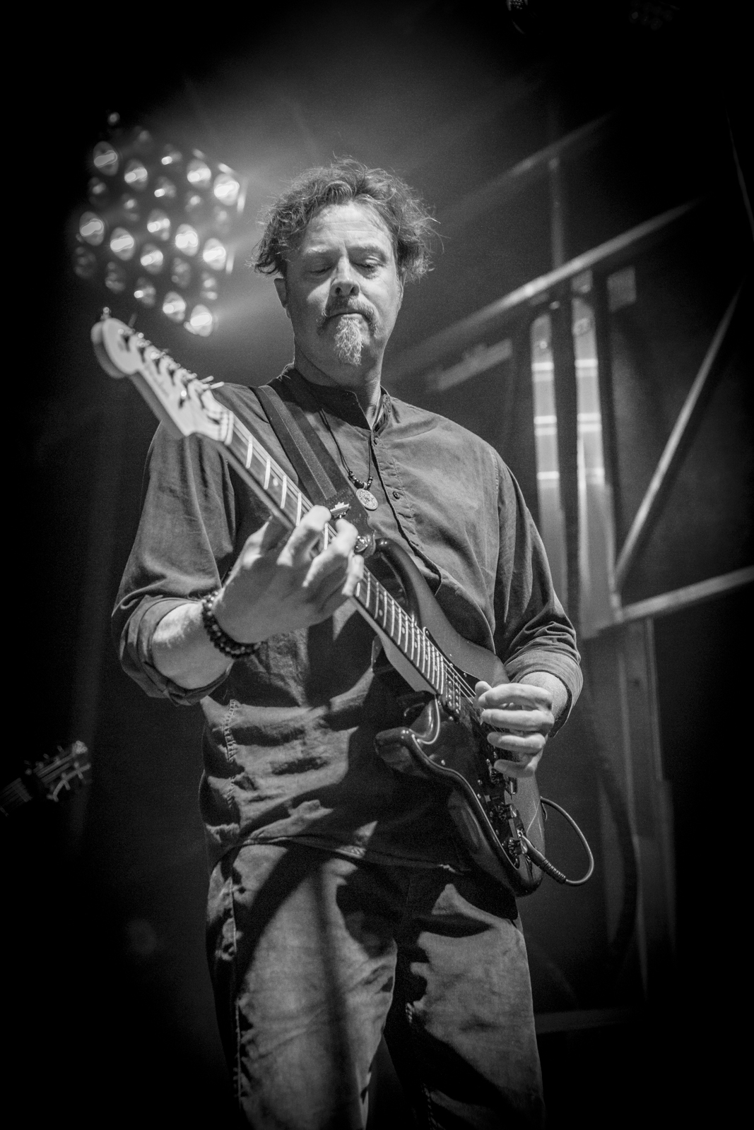 Lead guitarist backlit by a stage lamp