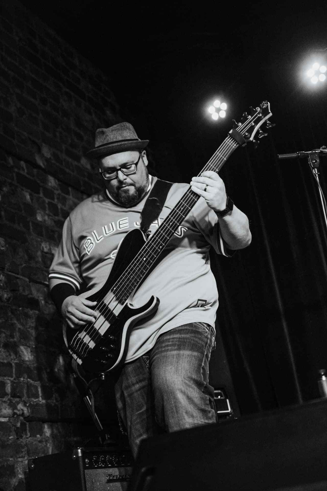 Matt in a Blue Jays jersey and fedora digging into a five-string bass