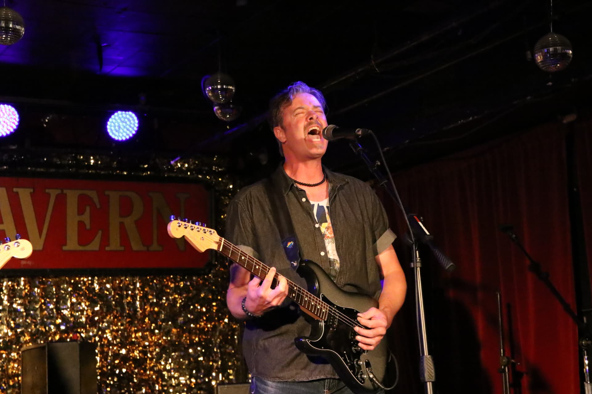 Dave singing lead into the mic with a black Stratocaster