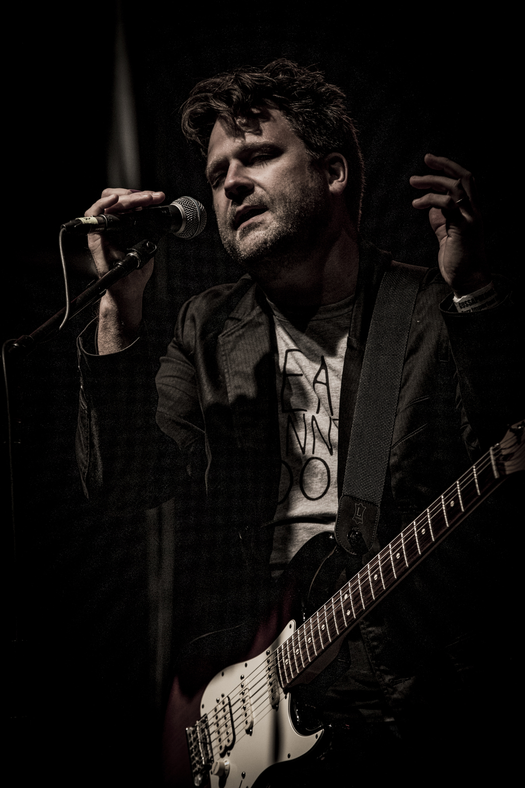 Kevin singing into the mic under a single hard light