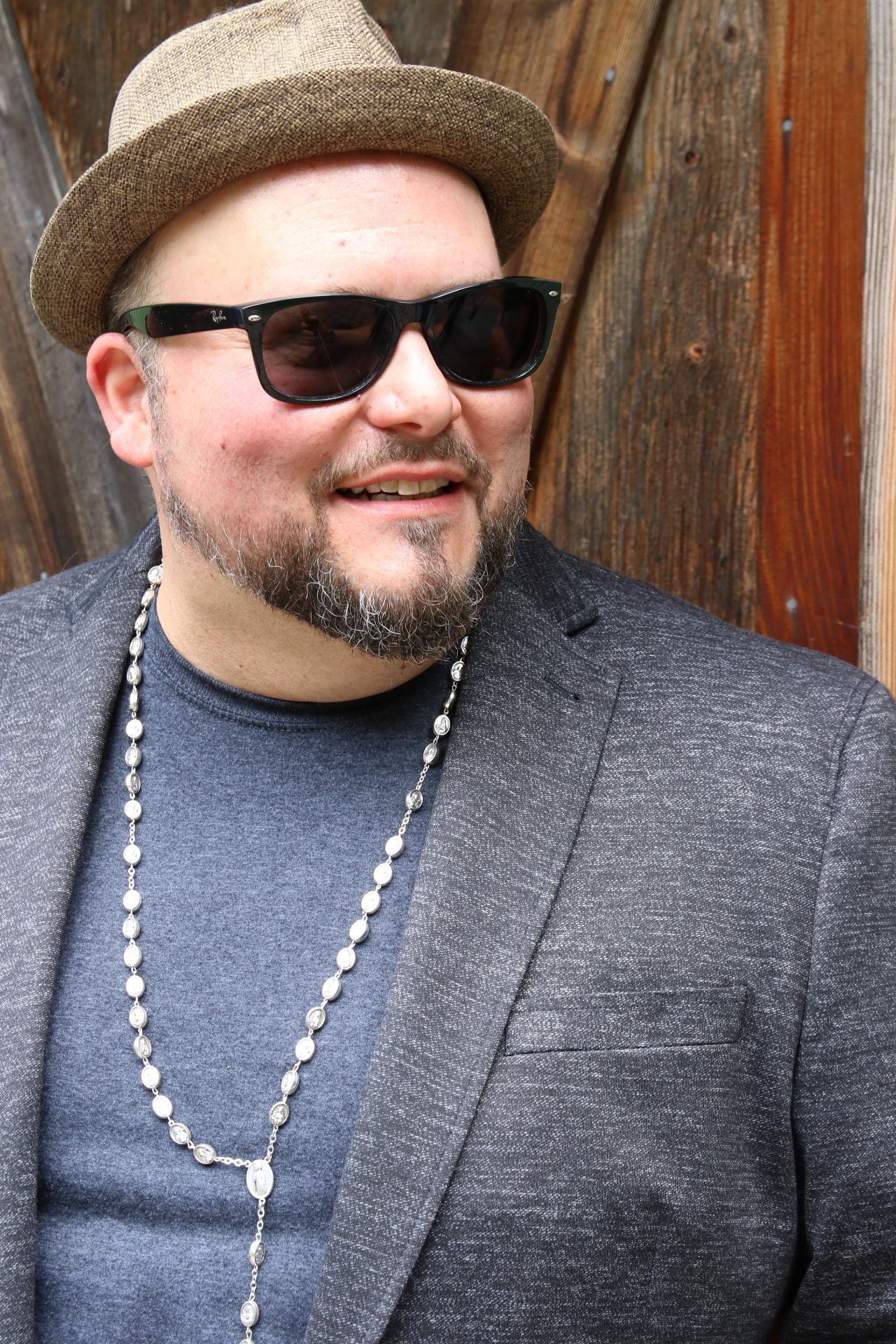Matt smiling in a fedora and sunglasses in front of a wooden barn door